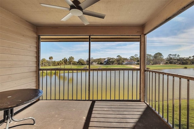 unfurnished sunroom featuring ceiling fan and a water view