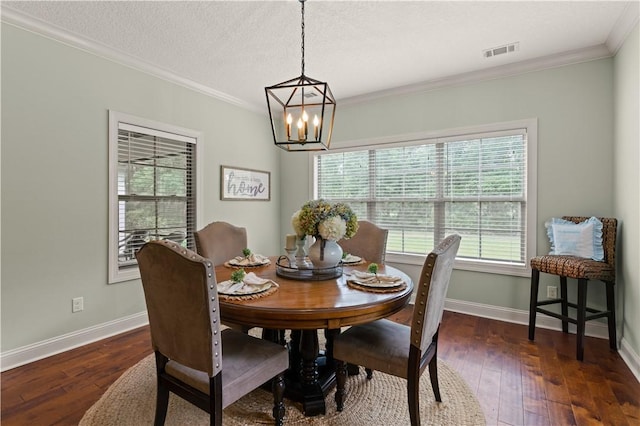 dining area featuring a textured ceiling, a notable chandelier, ornamental molding, and dark wood-type flooring