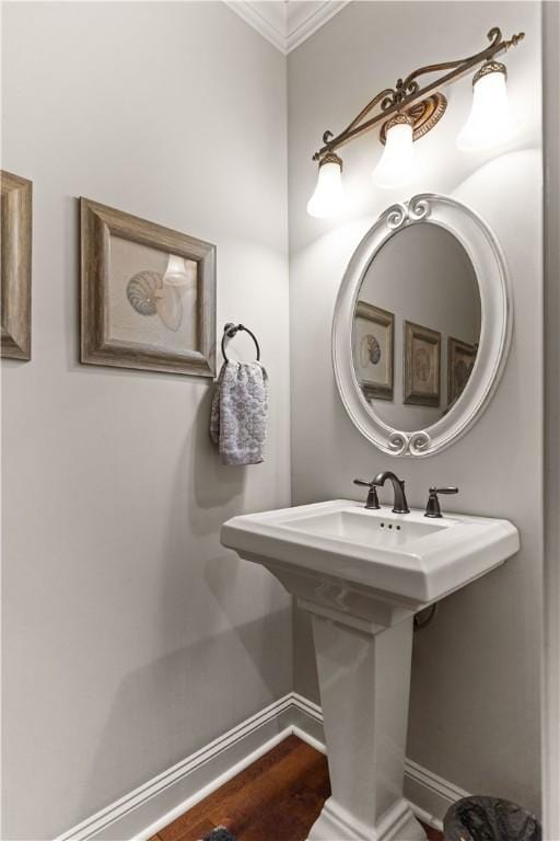 bathroom featuring hardwood / wood-style floors, ornamental molding, and sink