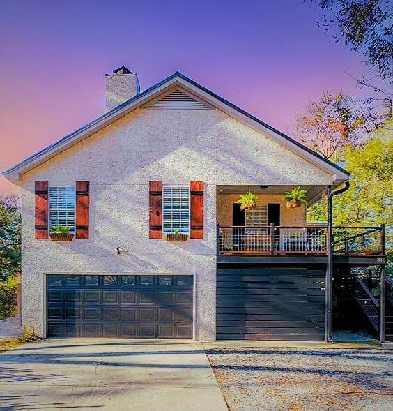 view of front of house with concrete driveway, stucco siding, a garage, and a chimney