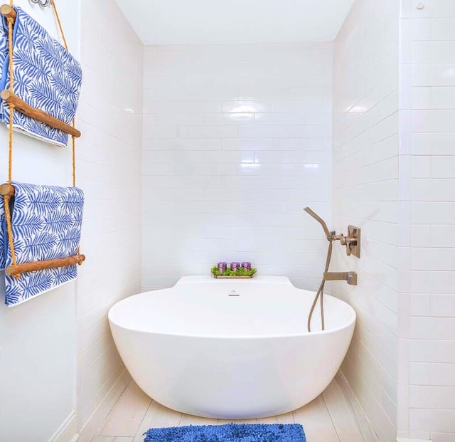 full bathroom with tile patterned flooring, tile walls, and a freestanding bath