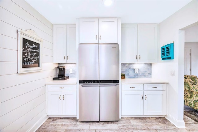 kitchen with tasteful backsplash, white cabinets, light countertops, and freestanding refrigerator