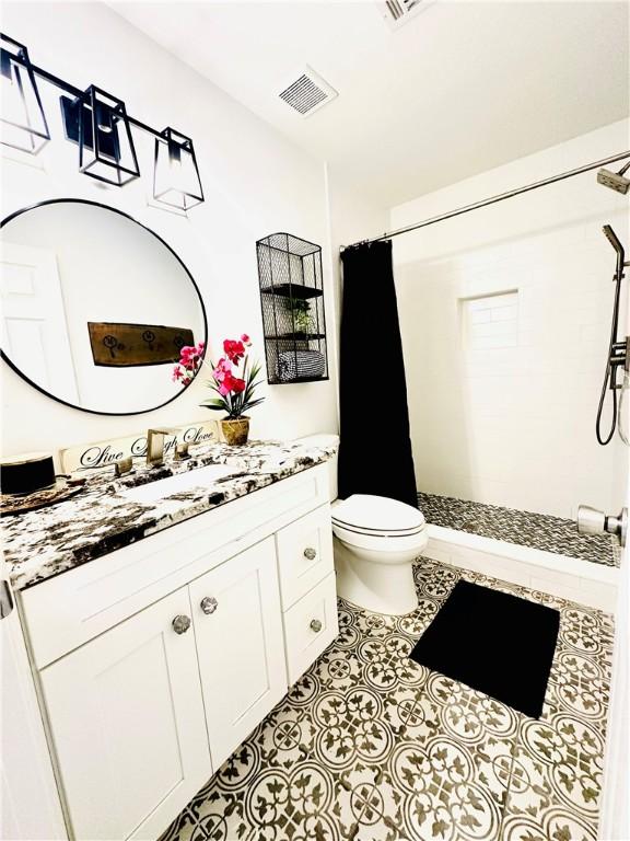 bathroom featuring vanity, curtained shower, tile patterned floors, and toilet