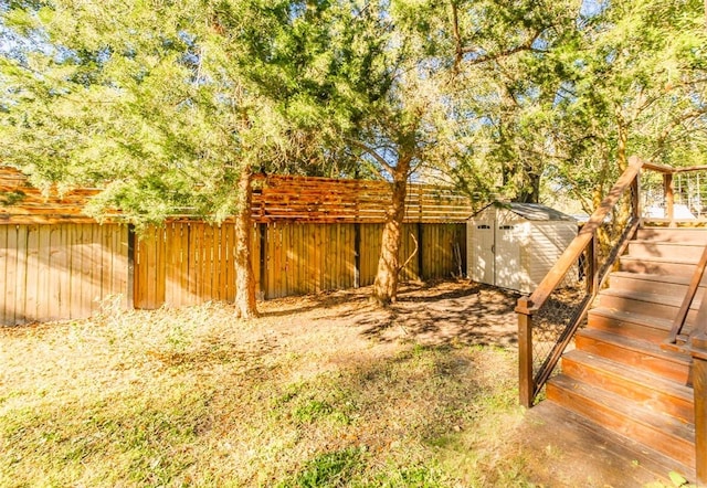 view of yard featuring a fenced backyard, a shed, stairway, and an outdoor structure