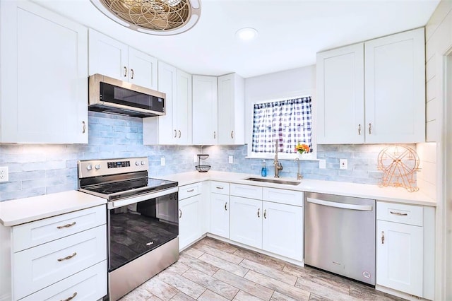 kitchen featuring tasteful backsplash, appliances with stainless steel finishes, light countertops, and a sink