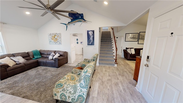 living area with vaulted ceiling, stairway, light wood finished floors, and ceiling fan