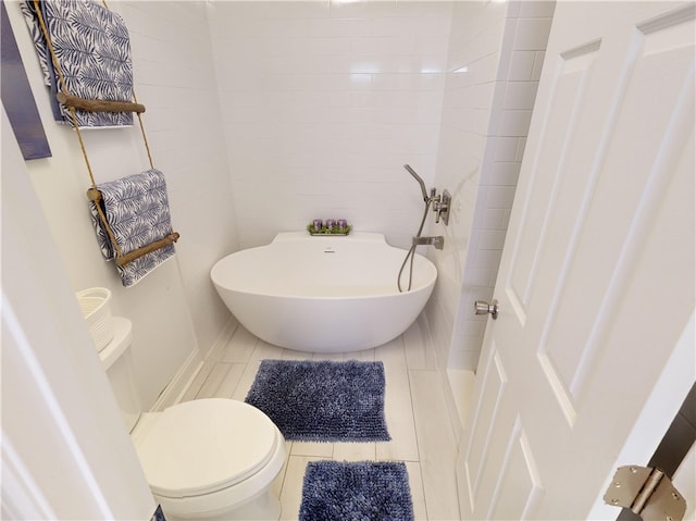 bathroom with toilet, a bathing tub, tile patterned flooring, and tile walls