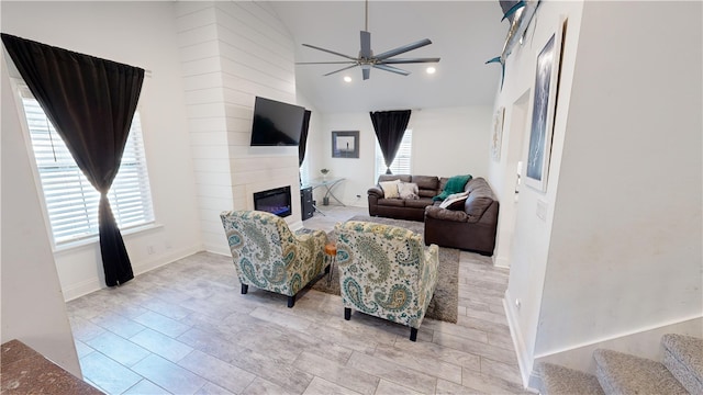 living room featuring ceiling fan, a fireplace, and high vaulted ceiling