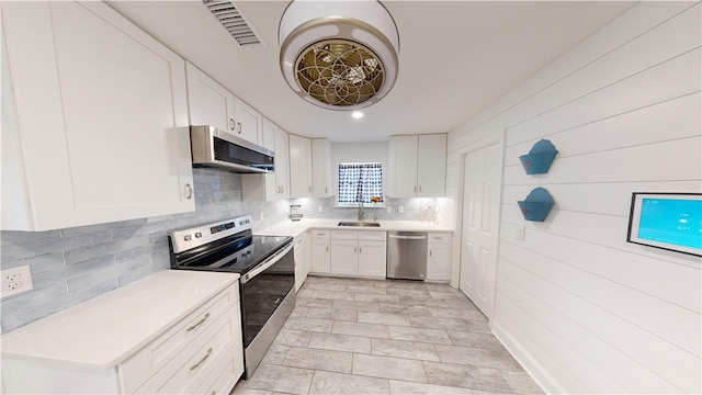 kitchen with sink, backsplash, stainless steel appliances, and white cabinets