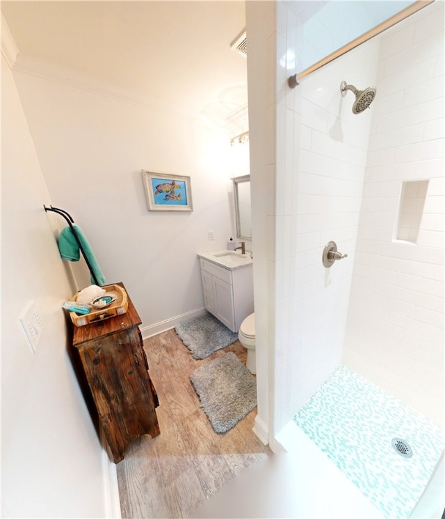 bathroom with vanity, hardwood / wood-style flooring, toilet, and tiled shower