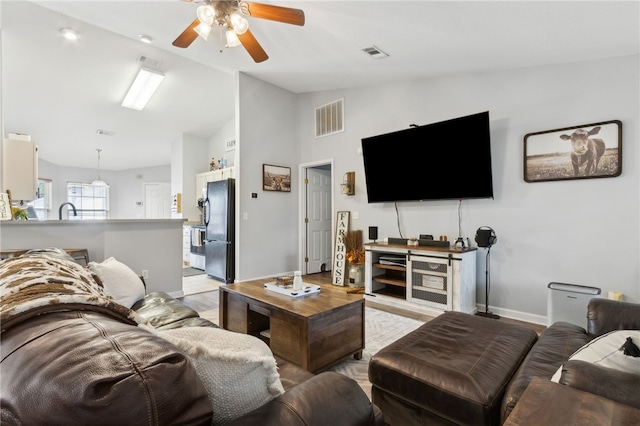 living room with baseboards, visible vents, a ceiling fan, and high vaulted ceiling