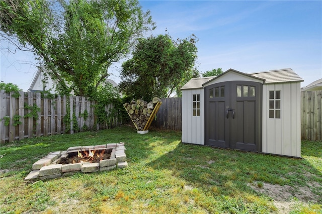 view of yard featuring an outdoor structure, an outdoor fire pit, a shed, and a fenced backyard