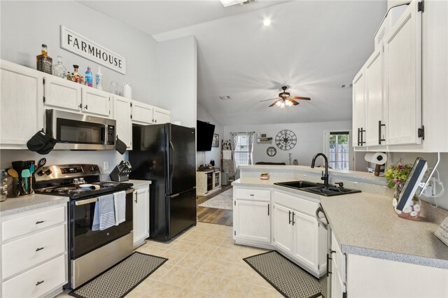 kitchen featuring a sink, stainless steel appliances, a peninsula, vaulted ceiling, and light countertops