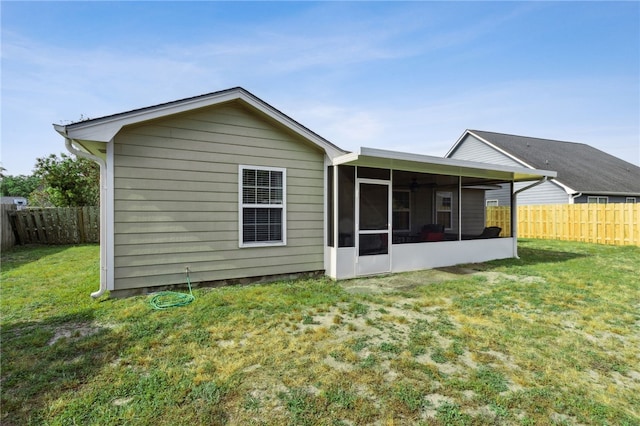 rear view of property with a yard, a sunroom, and a fenced backyard