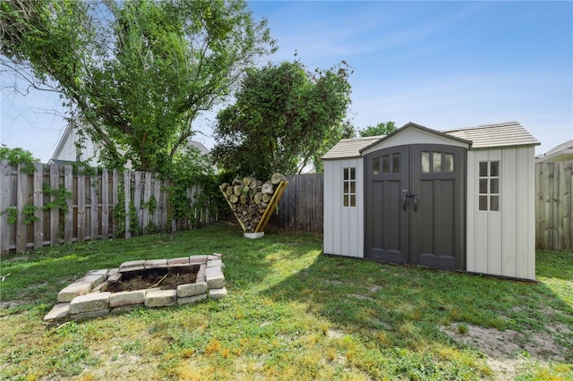 view of yard featuring an outdoor fire pit, a storage unit, an outbuilding, and a fenced backyard