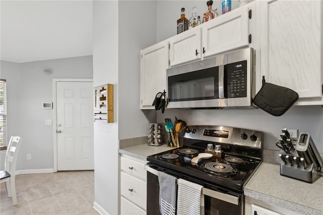 kitchen featuring stainless steel appliances, light tile patterned floors, light countertops, white cabinets, and baseboards