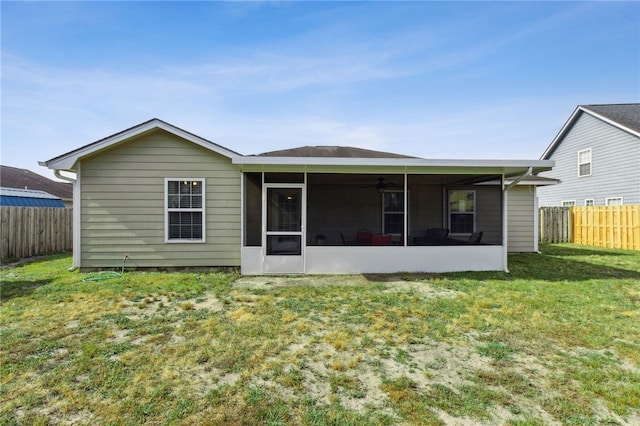back of property featuring a fenced backyard, a ceiling fan, a sunroom, and a lawn