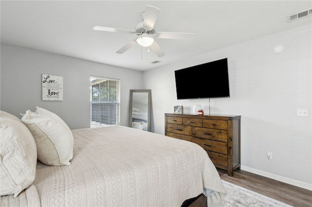bedroom with a ceiling fan, visible vents, wood finished floors, and baseboards