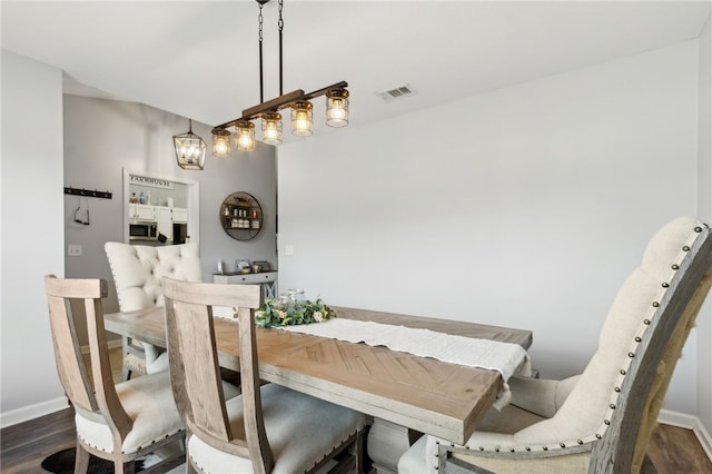 dining room with a notable chandelier, visible vents, baseboards, and dark wood-type flooring