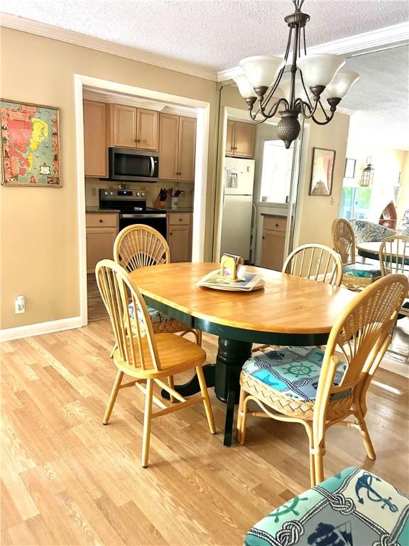 850 Mallery St Unit 4S, Saint Simons Island, GA 31522 - dining area with a textured ceiling, crown molding, a chandelier, light wood-style flooring, and baseboards
