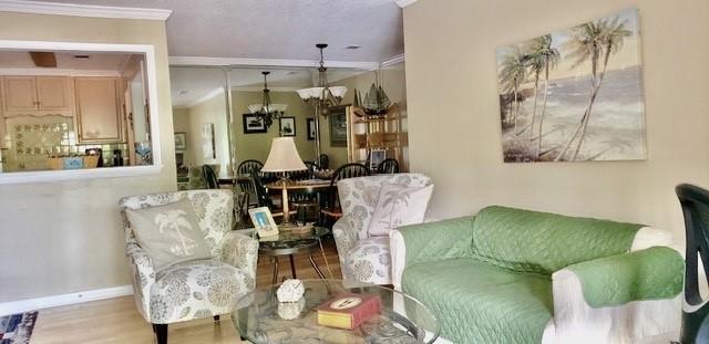living room with crown molding, baseboards, wood finished floors, and a chandelier