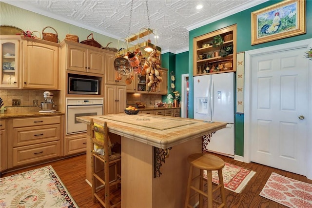 kitchen with tile countertops, white appliances, a breakfast bar, ornamental molding, and an ornate ceiling