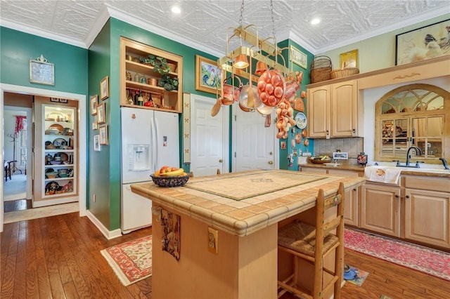 kitchen with an ornate ceiling, white refrigerator with ice dispenser, and light brown cabinets