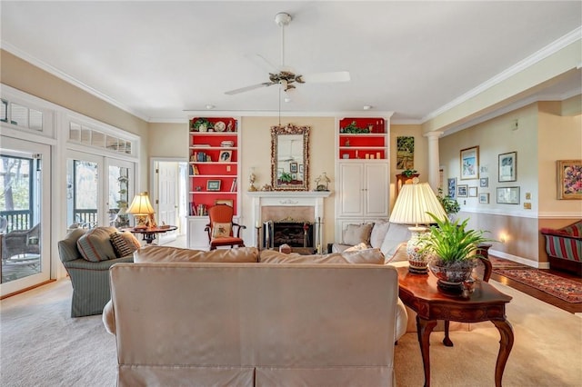 living room featuring a fireplace, decorative columns, ornamental molding, a ceiling fan, and light carpet