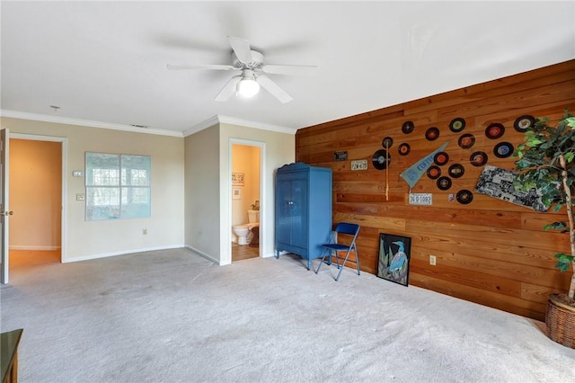 bedroom featuring wooden walls, baseboards, ceiling fan, ornamental molding, and carpet floors