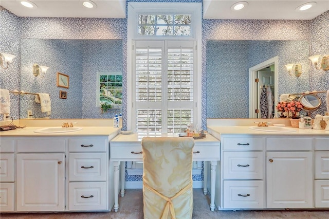 full bathroom with two vanities, a sink, and wallpapered walls