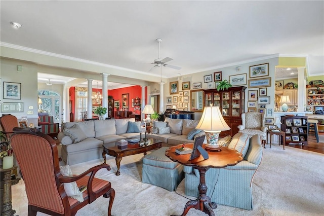 carpeted living area featuring ceiling fan, decorative columns, and crown molding