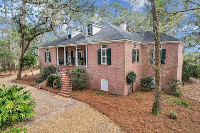 view of front of home with covered porch, a chimney, stairway, and brick siding