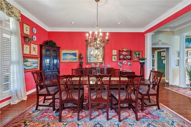 dining area featuring baseboards, wood finished floors, an inviting chandelier, crown molding, and ornate columns