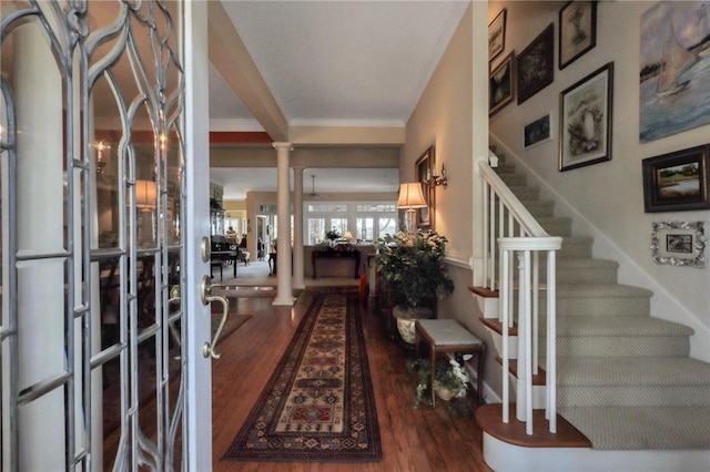 entryway featuring decorative columns, stairs, ornamental molding, and wood finished floors