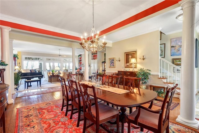 dining room with wood-type flooring, stairway, ornamental molding, ornate columns, and ceiling fan with notable chandelier