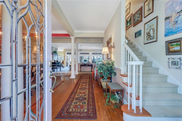 entrance foyer with stairway, wood finished floors, decorative columns, and crown molding