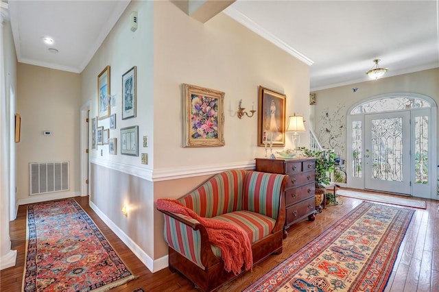 entrance foyer featuring ornamental molding, visible vents, baseboards, and hardwood / wood-style flooring