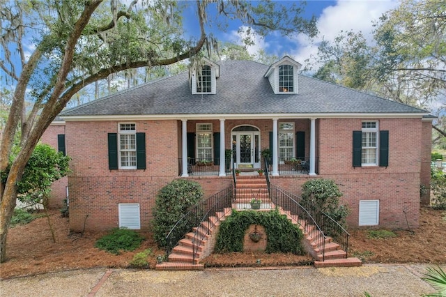 cape cod home with covered porch, brick siding, stairway, and crawl space