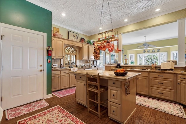 kitchen featuring dark wood-type flooring, a kitchen island, tile counters, an ornate ceiling, and crown molding