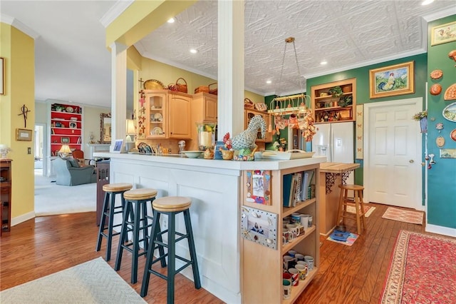 kitchen featuring ornamental molding, wood-type flooring, a kitchen breakfast bar, and open shelves