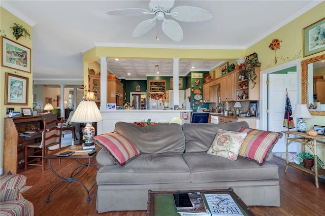 living area featuring ornate columns, a ceiling fan, ornamental molding, and wood finished floors