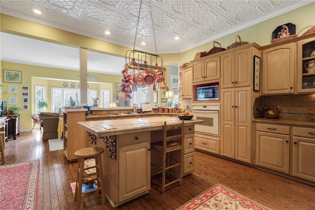 kitchen featuring an ornate ceiling, a breakfast bar, ornamental molding, built in microwave, and oven