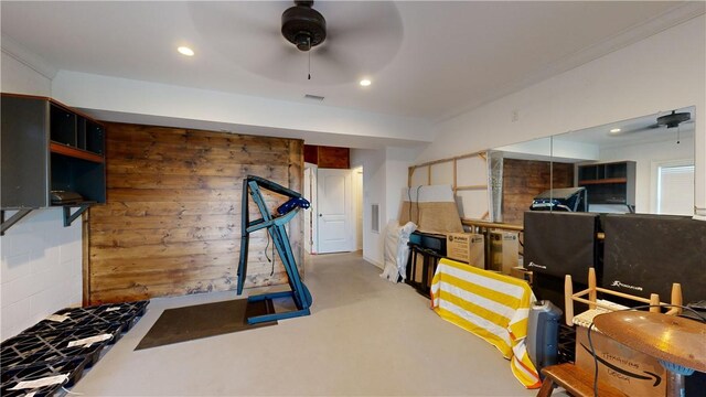 exercise area with ceiling fan, ornamental molding, and wooden walls