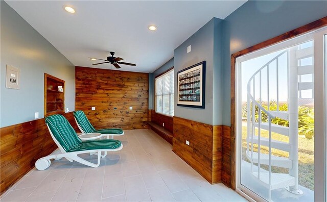 sitting room featuring plenty of natural light, wooden walls, and ceiling fan