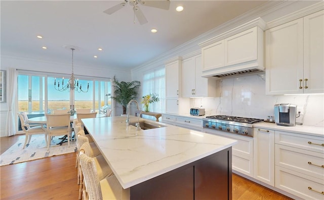 kitchen with white cabinets, decorative light fixtures, stainless steel gas stovetop, and sink