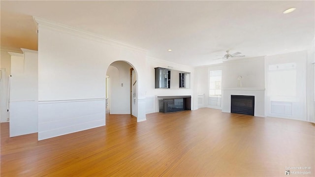 unfurnished living room with hardwood / wood-style floors, ceiling fan, and crown molding