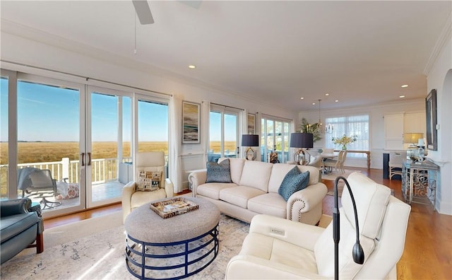 living room featuring light wood-type flooring, ceiling fan, and crown molding