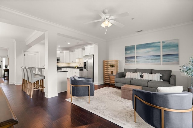 living area featuring visible vents, crown molding, dark wood-type flooring, and a ceiling fan