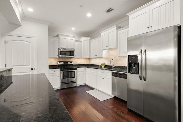 kitchen featuring visible vents, ornamental molding, backsplash, appliances with stainless steel finishes, and dark wood-style flooring