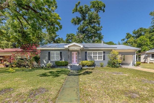 ranch-style home with metal roof, an attached carport, a front lawn, and driveway